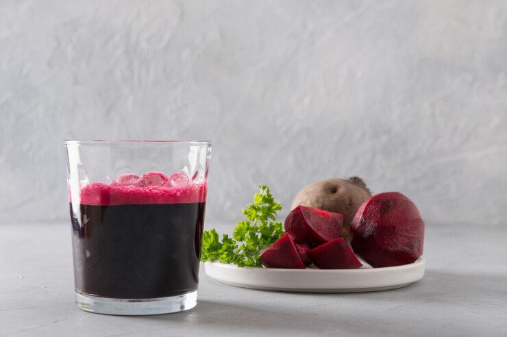 Glass of fresh beetroot juice garnish parsley on grey.
