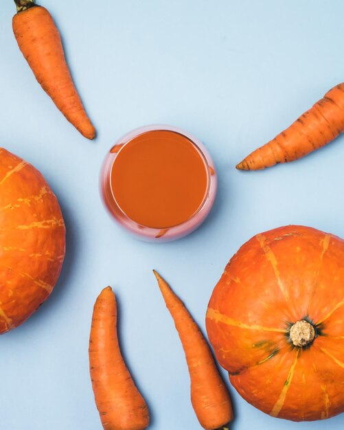 Bicchiere di carota fresca e succo di zucca bevanda dietetica sana vista dall'alto sfondo blu