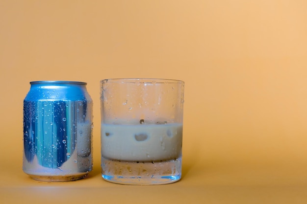 Glass of fresh cold brew coffee sitting next to its can over blurry background