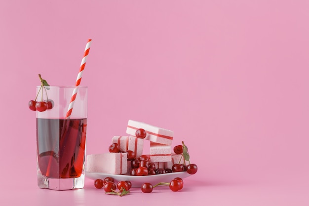 Glass of fresh juice with cherries on bright background