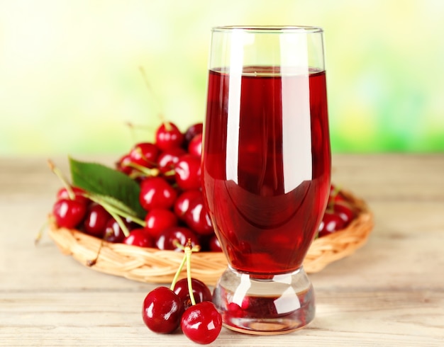 Glass of fresh juice with cherries on bright