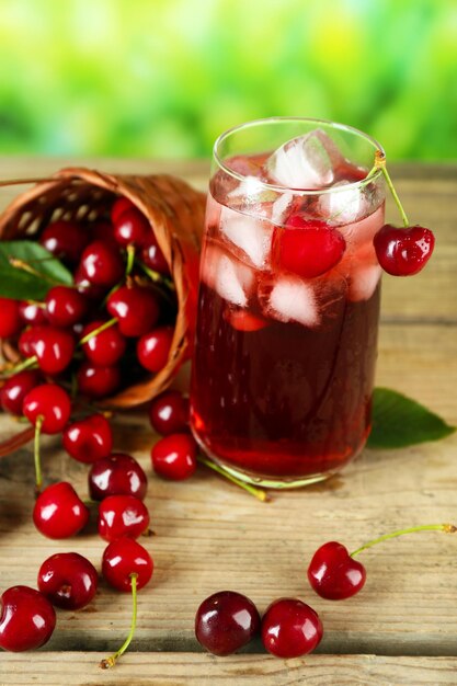 Glass of fresh juice with cherries on wooden table close up