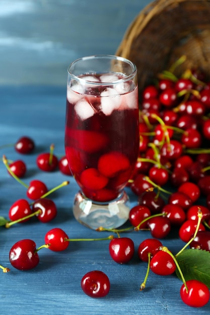 Glass of fresh juice with cherries on wooden table close up