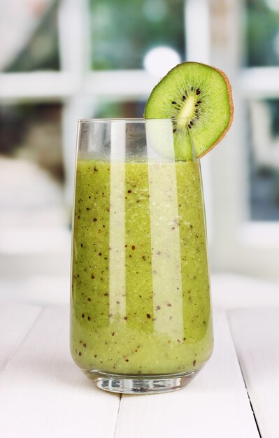 Glass of fresh kiwi juice on wooden table