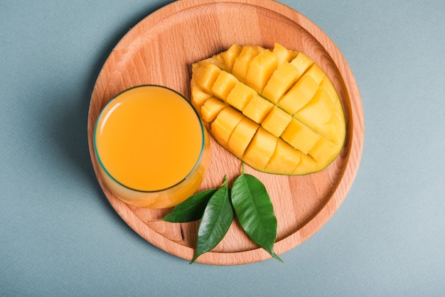 Bicchiere di succo di mango fresco e fetta di frutta arancione su sfondo grigio. messa a fuoco selettiva