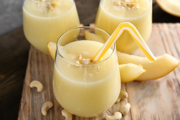 Glass of fresh melon smoothie on wooden board closeup