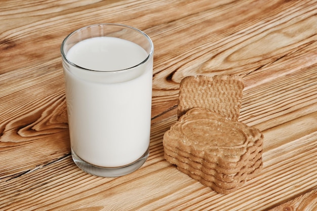 신선한 우유 한 잔과 나무 테이블에 있는 달콤한 쿠키 스택 아침 조식 개념
