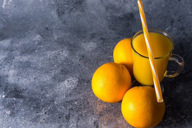 Glass of fresh orange juice, ripe orange fruits and slices