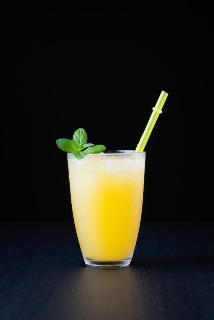 Glass of fresh orange juice with ice on a black background with a place for inscription