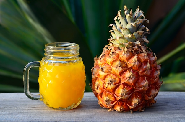 Glass of fresh pineapple juice and ripe pineapple fruit on rustic wooden table.Freshly squeezed pineapple juice with drinking straw.Healthy food,diet or vegan food concept.