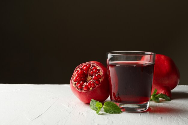 Glass of fresh pomegranate juice on white table