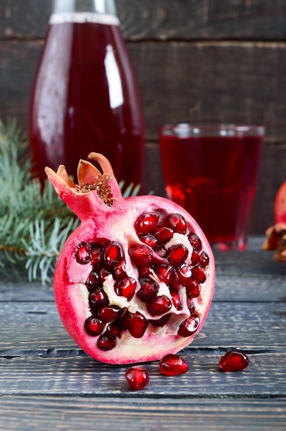 나무 테이블에 잘 익은 석류 과일과 함께 신선한 석류 주스 한 잔. 비타민과 미네랄. 건강 음료 개념입니다. 세로보기
