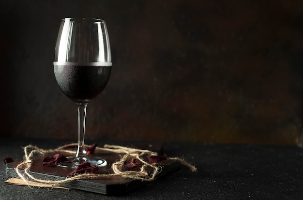 A glass of fresh red wine on a red board