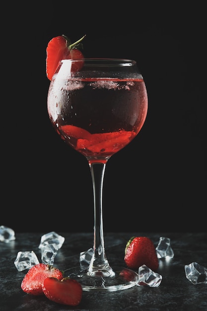 Glass of fresh strawberry cocktail on black smokey  table