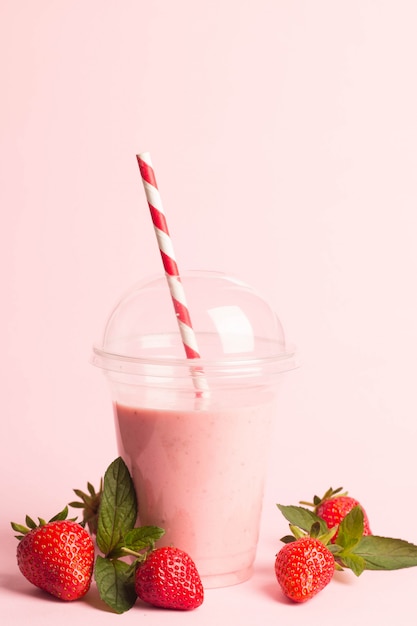 A glass of fresh strawberry milkshake on pink background