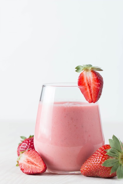 신선한 딸기 밀크 쉐이크, 스무디 및 분홍색, 흰색 및 나무 배경에 신선한 딸기의 유리. 건강 식품 및 음료 개념.