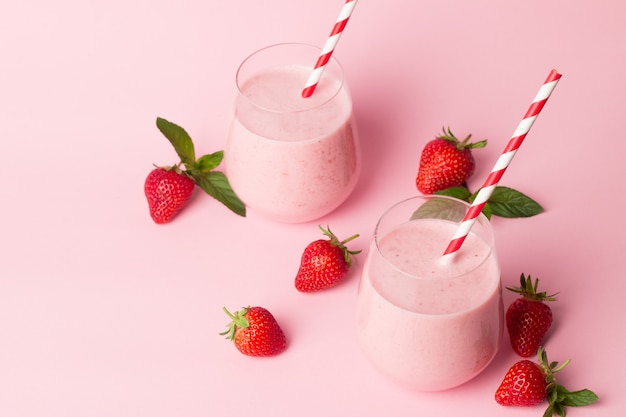 a glass of fresh strawberry smoothie on a pink background