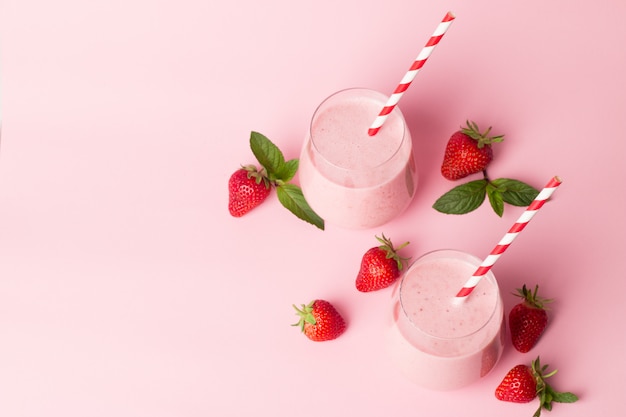 a glass of fresh strawberry smoothie on a pink background