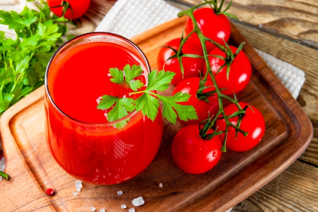 Glass of fresh tomato juice with tomatoes close up on the table.