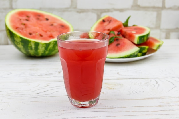 Glass of fresh watermelon juice on a white wooden table