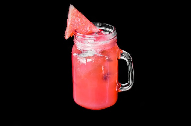 Glass of fresh watermelon juice with ice isolated on black background