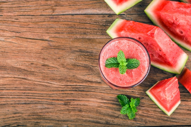 A glass of fresh watermelon juice on a wooden board