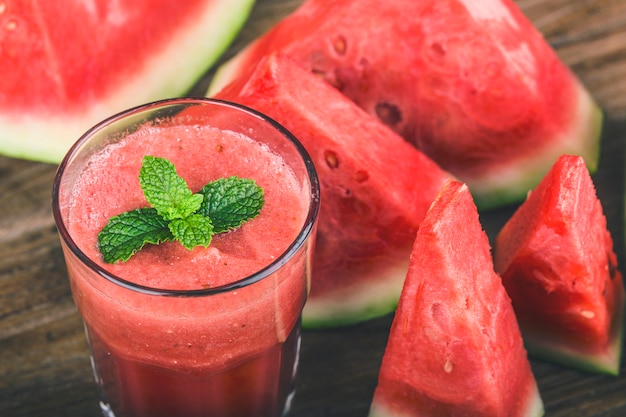 A glass of fresh watermelon juice on a wooden board