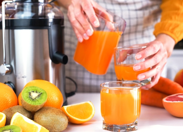 glass of freshly squeezed fruit juice the girl pours juice into a glass on the background