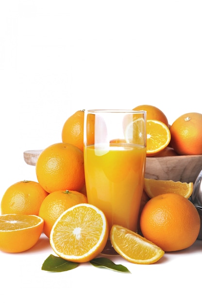 Glass on freshness orange juice among heap of fruits on white background 