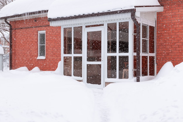 Glass front door of red brick house during heavy snowfall Frosty nature scenery in winter