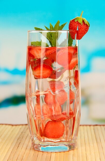 Foto bicchiere di bevanda alla frutta con cubetti di ghiaccio su sfondo blu