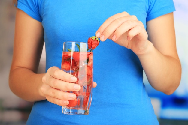 Glass of fruit drink with ice cubes in hand