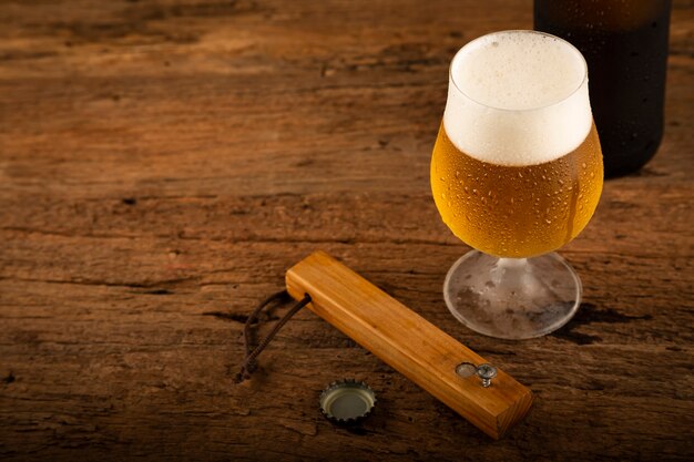 Bicchiere pieno di birra fredda sul tavolo di legno