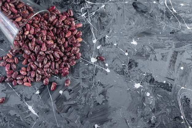 Glass full of raw beans placed on stone background. 