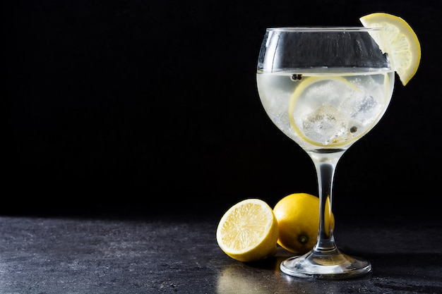 Photo glass of gin tonic with lemon on black background copy space