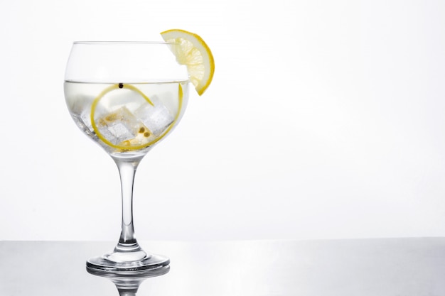 Bicchiere di gin tonic con limone isolato su bianco