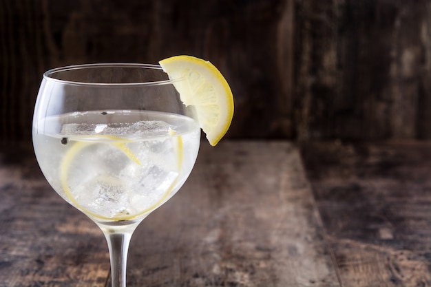 Glass of gin tonic with lemon on wooden table 