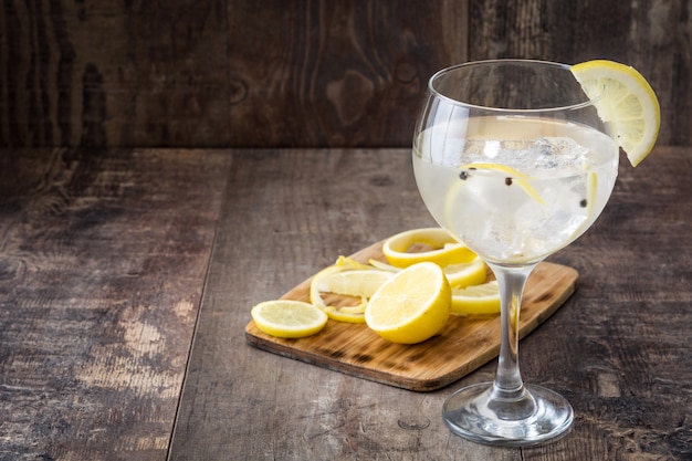 Glass of gin tonic with lemon on wooden table 