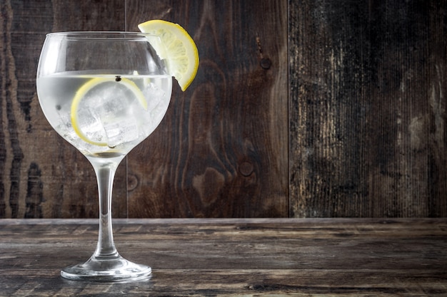 Glass of gin tonic with lemon on wooden