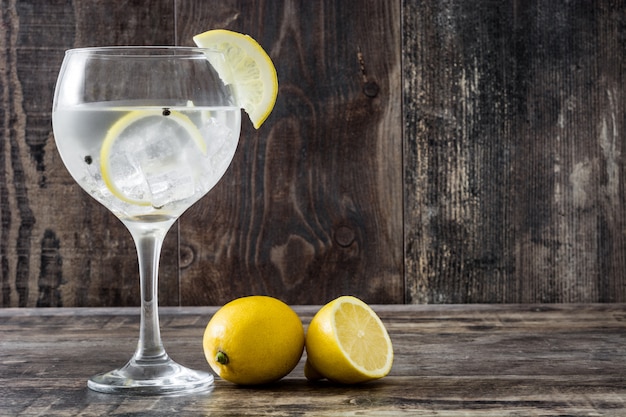 Glass of gin tonic with lemon on wooden