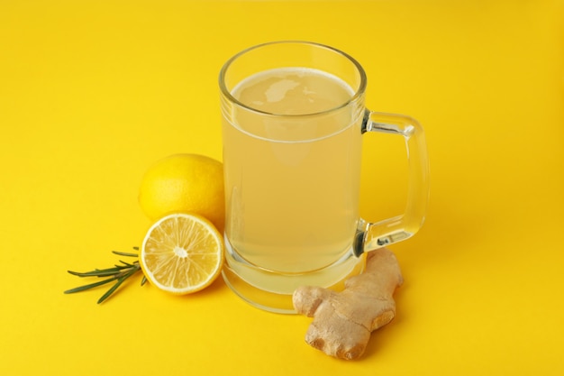 Glass of ginger beer and ingredients on yellow