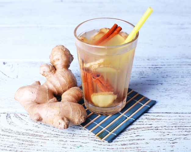 Glass of ginger drink on bamboo napkin on wooden background