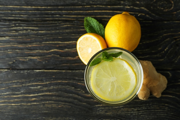 Glass of ginger - lemon drink and ingredients on wooden table