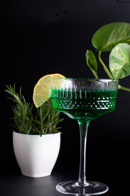 A glass glass of cream with colored drinks on a black background with green tropical leaves Alcoholic fruit cocktail