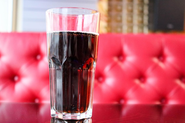 Glass glass with brown sweet cold tasty refreshing lemonade on the table in a cafe in the evening