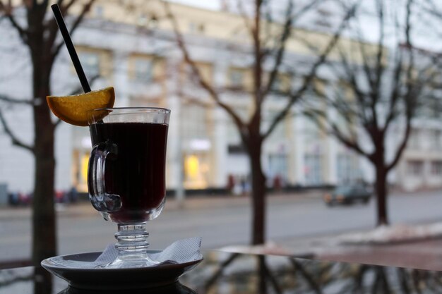 Photo a glass glass with brown tasty hot fragrant alcoholic mulled wine on a table in a cafe in the evenin