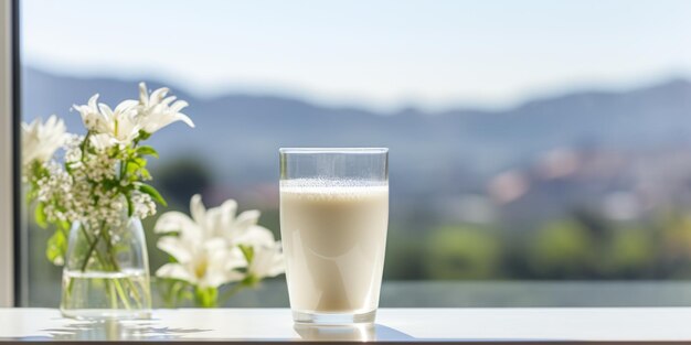 A glass glass with milk stands on a marble table with a bouquet of flowers