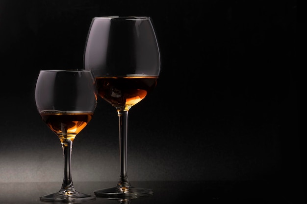 Glass glasses on a thin stem on a black background with wine