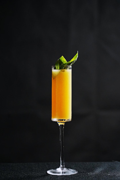 A glass of golden champagne cocktail on a black background