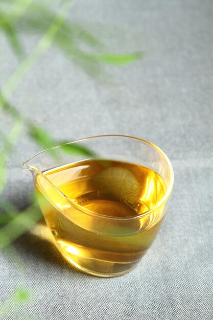 A glass of golden syrup sits on a table next to a plant.